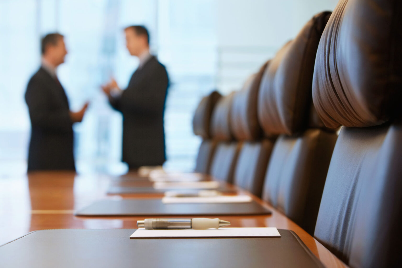 A conference room with two people standing in the background.