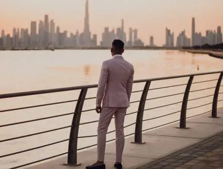 A man in a suit standing on the side of a river.