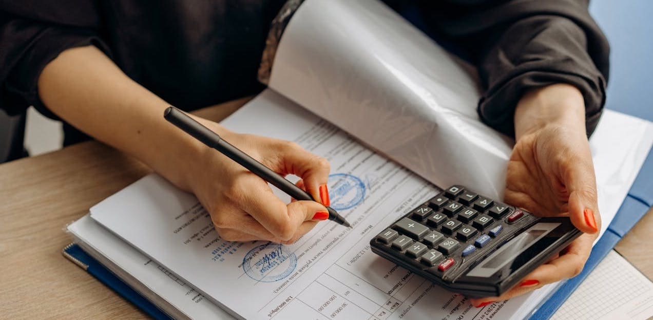 Person calculating their finances on paper and a calculator
