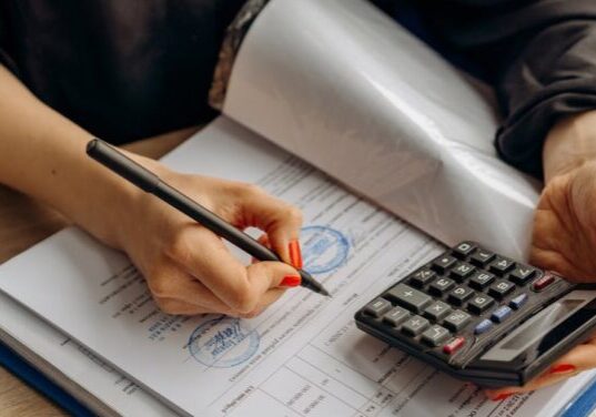 Person calculating their finances on paper and a calculator